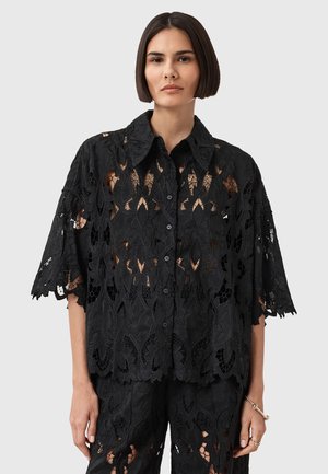 Black lace blouse with floral cutouts, collared neckline, short sleeves, and a loose fit. Features button closure and textured fabric.