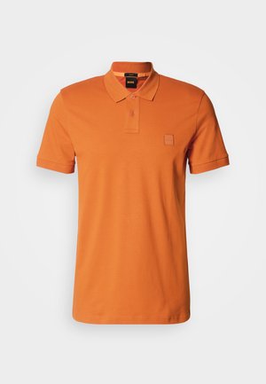 Oransje polo skjorte med krage, kortermet, to knapper og et preget logo på brystet. Glatt stofftekstur.