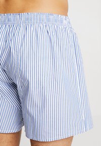 Men's blue and white striped cotton shorts. Elastic waistband, loose fit, and smooth texture with vertical pattern.