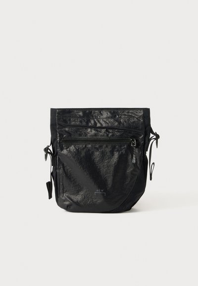 Black waterproof bag made of textured nylon, featuring a top zip closure, front zip pocket, and adjustable cord sides.