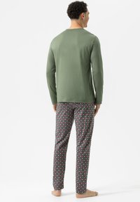 Groene, lange mouwen shirt gecombineerd met gestreepte pyjama broek met rode en blauwe cirkels op een grijze achtergrond; katoenen materiaal.