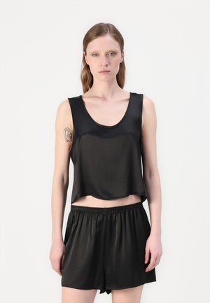 Svart, kort tanktop i glatt stoff, kombinert med svarte elastiske shorts med liv. Begge plaggene har et enkelt, minimalistisk design.