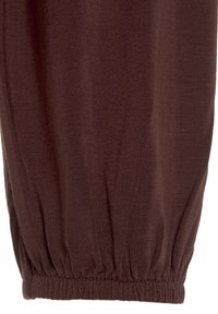 Närbild av brun tyg elastisk manschett med fin stickad struktur och rynkor som bildas vid fållen.