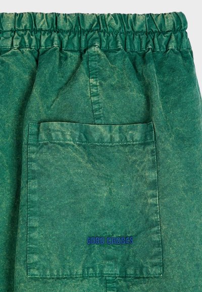 Groene katoenen shorts met elastische tailleband. Beschikt over een achterzak en het "GOBO CHOSES" logo in het blauw naast de zak. Lichtjes gestructureerde stof.