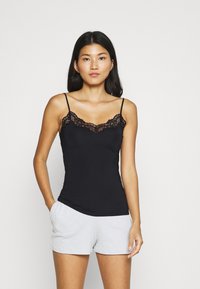 Black camisole with lace trim at the neckline, featuring thin spaghetti straps. Paired with light gray shorts, showcasing a soft texture.