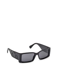 Gafas de sol negras con montura cuadrada, con un acabado brillante, lentes oscuros y logo en relieve en los laterales. Diseño minimalista.