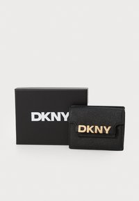 Crni DKNY novčanik od teksturiranog sintetičkog materijala, s zlatnim logotipom sprijeda i kompaktnih, presavijenim dizajnom. Dolazi u crnoj kutiji.