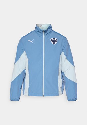 Svetlomodrá bunda s tmavšími modrými akcentmi, so zipsom, elastickými manžetami a logom na hrudi. Vyrobená z ľahkej, štruktúrovanej tkaniny.