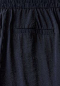 Shorts en tissu bleu marine avec une taille élastique, dotés d'une poche arrière et d'une finition lisse, légèrement texturée.