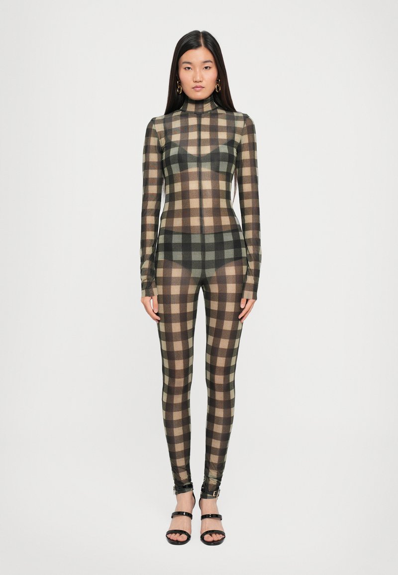 Transparent mesh bodysuit featuring a brown and beige check pattern, long sleeves, high neckline, and fitted legs. Styled with black strappy sandals.