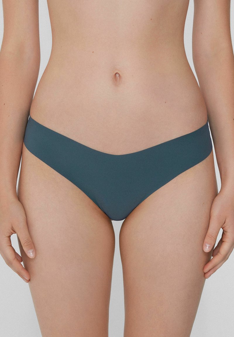 Bikini w kolorze turkusowym z gładką fakturą, niskim stanem i minimalnym pokryciem. Bezszwowe krawędzie zwiększają komfort i dopasowanie.