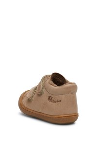 Stivale per bambino in pelle beige chiaro con una finitura morbida e texture. Presenta due cinturini in velcro e una suola in gomma. Branding sul tallone esterno.