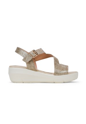 Sandali wedge metallici dorati con cinturini incrociati, fibbia regolabile e una suola chunky di colore chiaro. Texture morbida e design aperto.