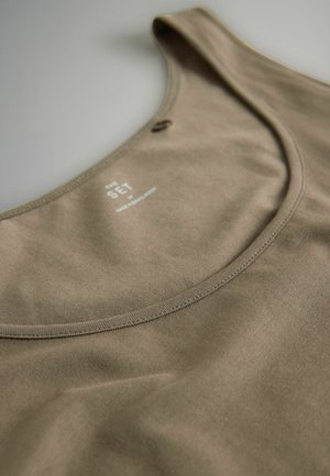 Bézsszínű trikó lekerekített nyakkivágással és vékony pántokkal. Puha, texturált anyagból készült, a nyaknál minimális márkajelzéssel.