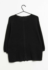 Czarny, oversize sweter dzianinowy, z zaokrąglonym dekoltem, długimi rękawami, otwartymi rozcięciami po bokach oraz teksturowanym, prążkowanym materiałem.