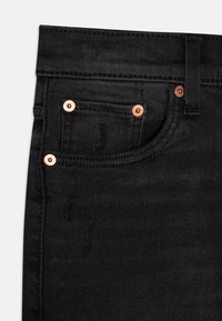Jeans negri din denim, cu accesorii din cupru, design cu cinci buzunare și detalii subtile de uzură. Materialul are un finisaj neted, ușor texturat.