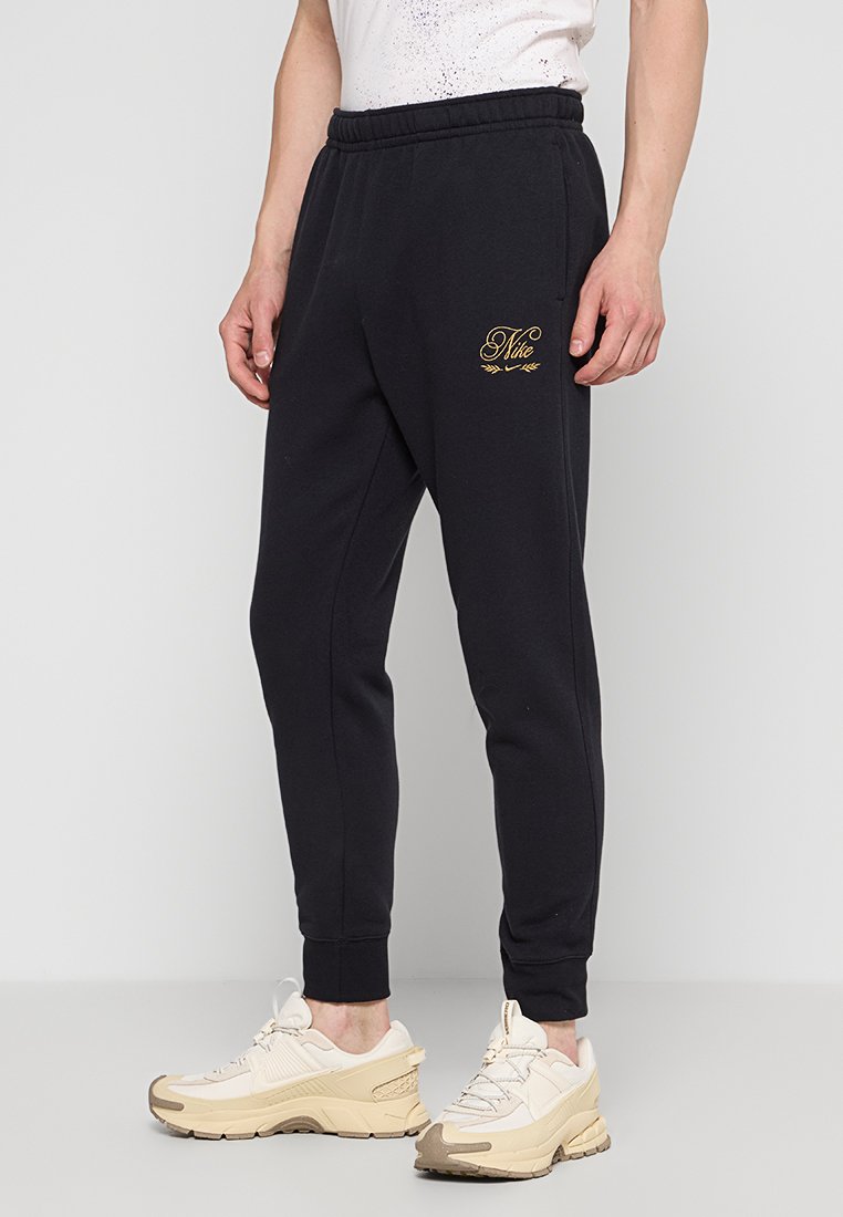 Schwarze Sweatpants aus weichem Stoff, mit schmalem Schnitt und elastischem Bund. Goldenes Logo-Detail auf dem linken Oberschenkel.