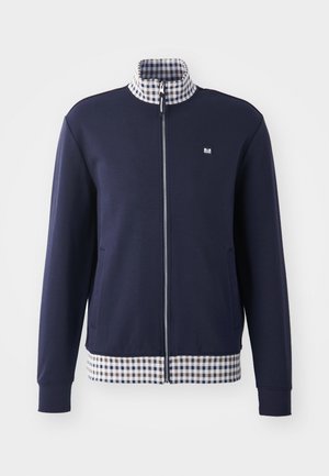 Navy zip-up jacket with a high collar, white and blue checkered inner lining, and checkered hem. Features side pockets and elastic cuffs.
