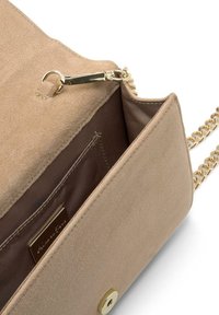 Bolso cruzado de ante beige con una correa de cadena dorada, que cuenta con un bolsillo con cremallera y un forro interior suave con una pequeña etiqueta de la marca.