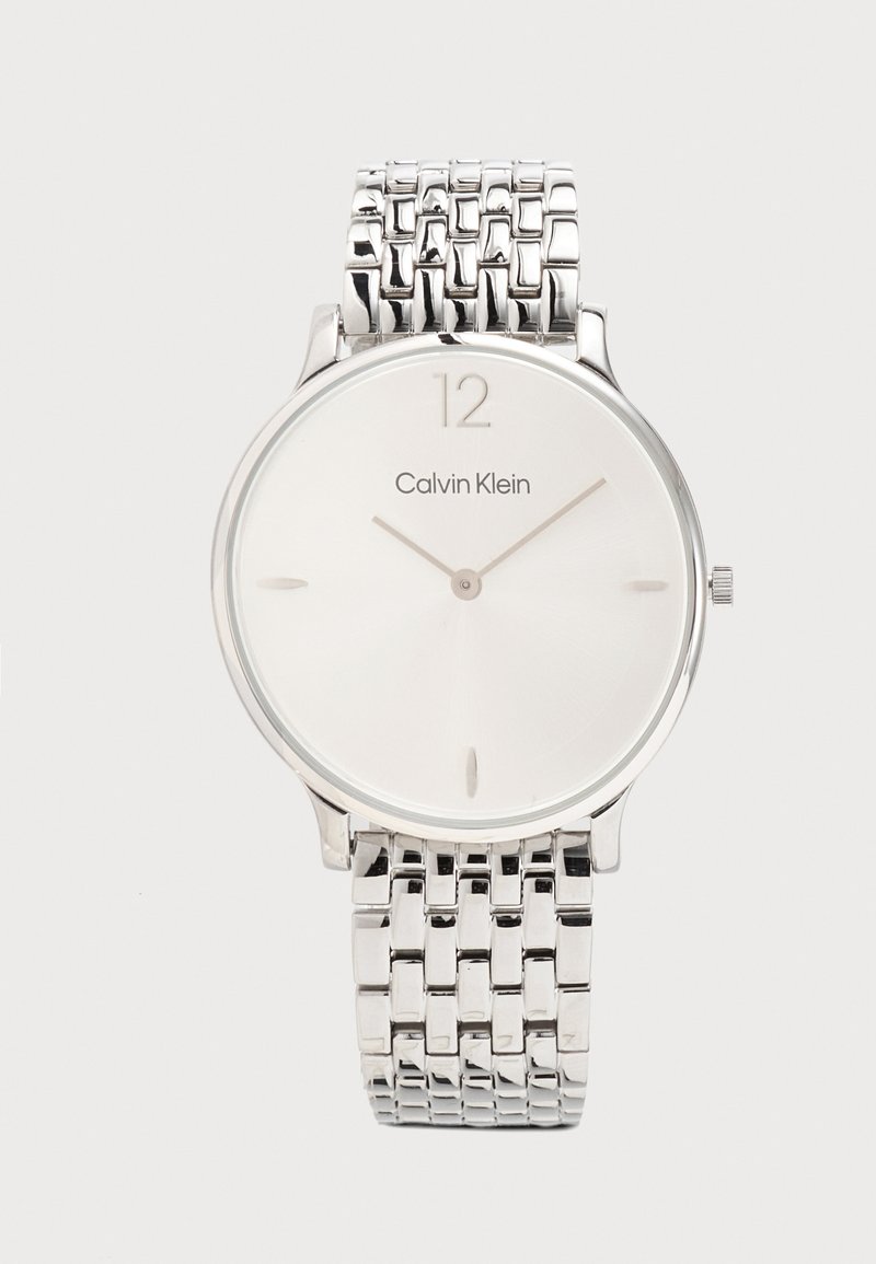 Montre-bracelet fine argentée Calvin Klein avec un cadran blanc minimaliste, des index argentés et un bracelet métallique à maillons.