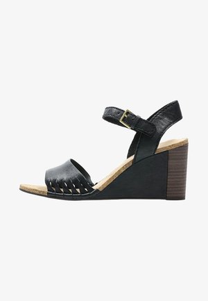 Sandalo wedge nero con tomaia in pelle testurizzata e design a frange, cinturino alla caviglia regolabile e suola in sughero con tacco in legno.