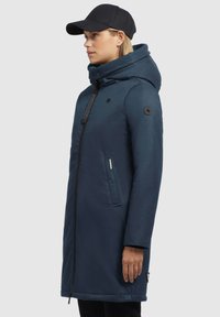 Navyblaue Kapuzenparka mit Reißverschluss vorne, zwei Seitentaschen und strukturiertem Finish. Hat ein Logo-Patch am Ärmel und eine Kapuze.