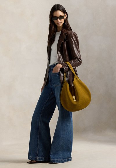 Καφέ δερμάτινο σακάκι, γκρι τοπ, φαρδιά μπλε τζιν και μια τσάντα μουσταρδί κίτρινου σουέτ με χρυσή λεπτομέρεια. Ομαλές υφές και ευρείες φόρμες.