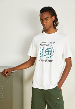 Witte katoen t-shirt met afgeprinte tekst in groen en zwart. In combinatie met olijfgroene cargo-broeken en een metalen locker op de achtergrond.
