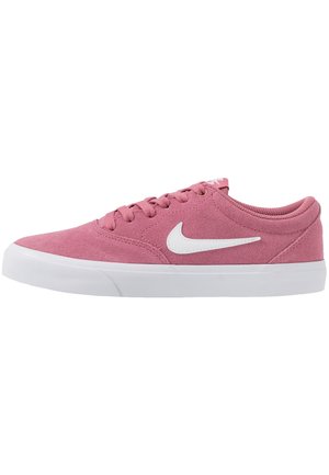 Niskie różowe zamszowe buty sportowe z białym logo Nike Swoosh, białą gumową podeszwą i różowymi sznurowadłami na białym tle.