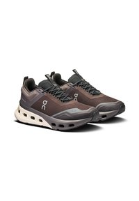 Brown mesh sneakers with a lightweight design, featuring black accents, a cushioned sole, and a distinctive hole pattern for breathability.