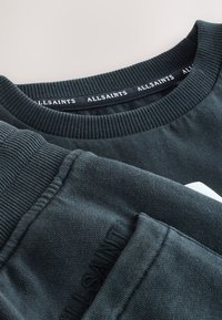 Dunkelgrauer gerippter Crewneck-Sweatshirt und passende Sweatpants mit subtil geprägtem AllSaints-Logo auf dem Stoff.