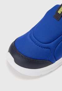 Baskets bleues avec une tige en textile lisse, un embout en synthétique navy durable, et une semelle extérieure en caoutchouc blanc avec des détails texturés.