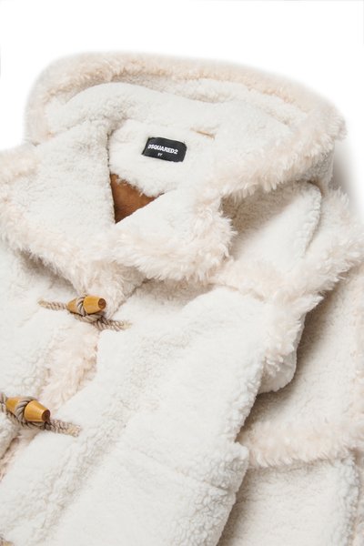 White fleece coat with a soft texture, featuring a beige trim, wooden toggles, and a plush collar. Lined with brown material inside.
