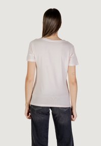 T-shirt di cotone rosa chiaro con maniche corte e collo a giro. La vista posteriore mostra una texture liscia e una silhouette aderente. Indossato con jeans scuri.