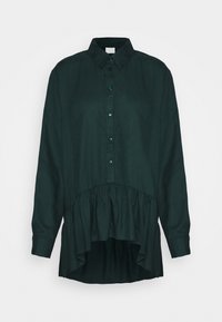 Mörkgrön långärmad blus med krage, framknäppning och samlad hög-låg kant som fladdrar nedanför midjan.