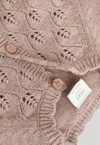 Gilet en tricot pour bébé en rose doux, avec un motif en dentelle, des bords côtelés et deux boutons ronds beige. L'étiquette indique "NEXT Baby."