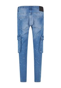Blue denim cargo pants with a slim fit, featuring two side pockets, white splatter details, and a black waistband accent.