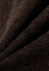 Bruin gebreide stof met een zachte, gestructureerde oppervlakte, met subtiele variaties in kleur en dikte, met zachte plooien en draperingen.