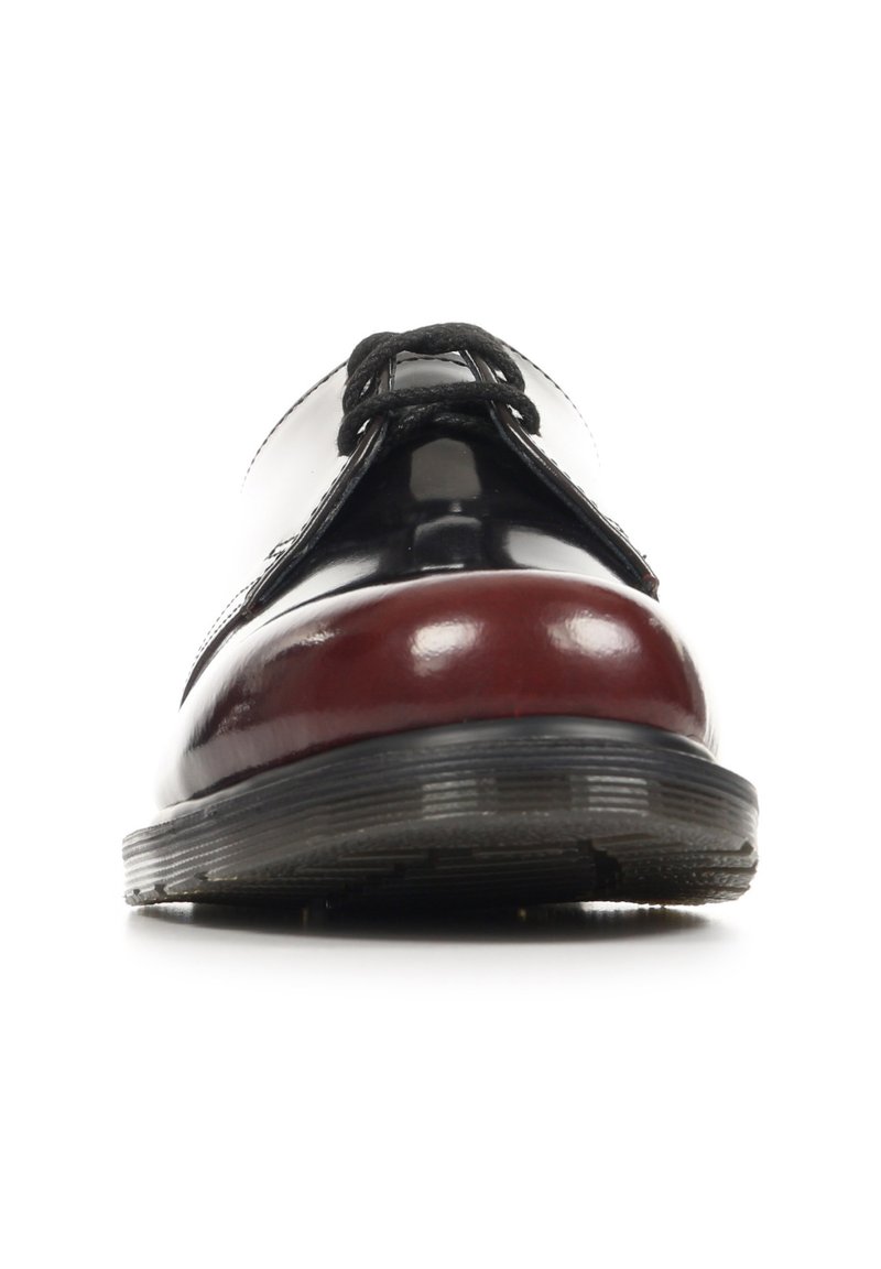 Glänzender schwarz-dunkelroter Lederschuh mit schwarzen Schnürsenkeln, von vorne gezeigt, der eine abgerundete Spitze und eine dicke Gummisohle hervorhebt.