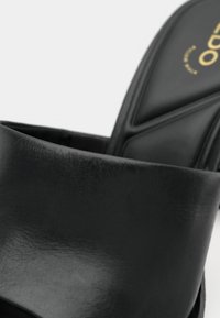 Fekete bőr magas sarkú szandál párnázott talpbetéttel és nyitott orr-résszel.