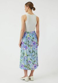 Ärmlös vit tanktopp i kombination med en midiklänning i blå blommönster, med lila, gröna och blå mönster; slät tygkvalitet; elastisk midja.