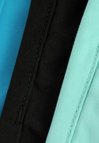 Pezzetti di tessuto di cotone in turchese, azzurro chiaro e nero. Ogni pezzo mostra trame testurizzate con cuciture visibili lungo i bordi.