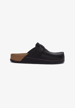 Black leather slip-on clog with cork footbed, adjustable strap, and stitched detailing on sole against white background.