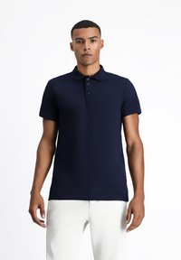Granatowa koszulka polo wykonana z gładkiego materiału, z kołnierzykiem, zapięciem na trzy guziki i krótkimi rękawami.
