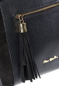 Borsa in pelle nera con texture, dotata di una cerniera dorata e di un elegante nappina in suede nera attaccata vicino alla cerniera.