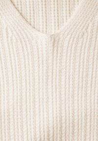 Maglione lavorato a maglia color crema con scollatura a V. Design testurizzato e rigato su tutta la superficie. Aspetto morbido, realizzato in tessuto accogliente.