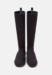 Svarta knähöga strumpor i ribbat material med en slät yta; har en dragflik på toppen för enkel påklädning.
