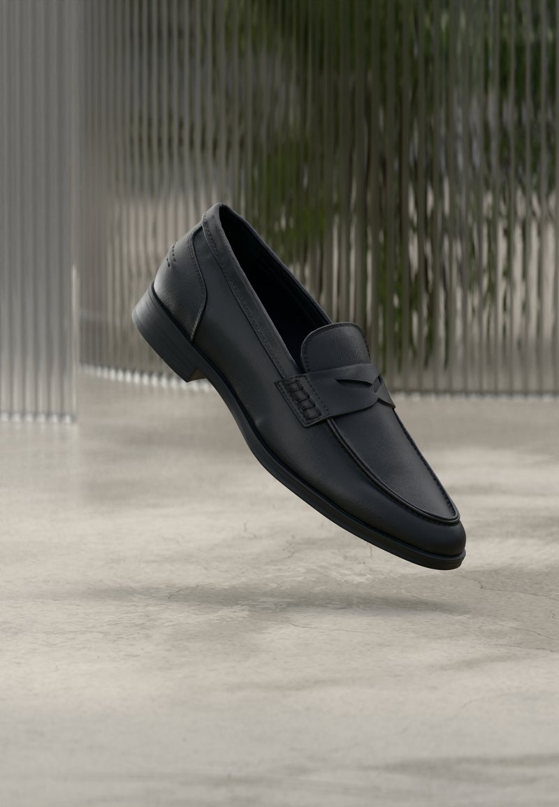 Mocassin en cuir noir à finition lisse, bout pointu et détails cousus sur le dessus. Talon bas et design minimaliste.