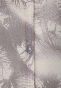 Leichtes Gewebe mit einem grauen und cremigen Palmenblattmuster. Hat eine glatte Textur und sichtbare Nähte entlang der Naht.