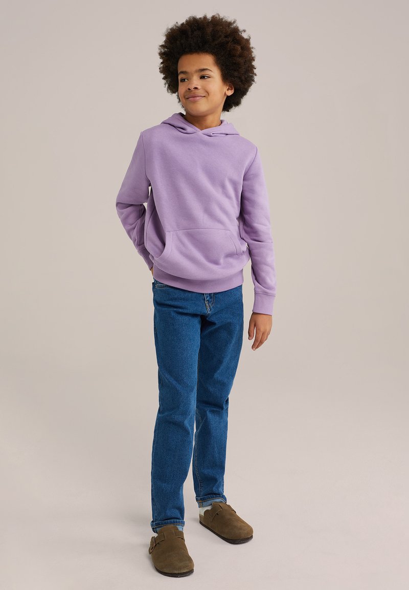 Lavendelfärgad hoodie med känguruficka, parat med blå jeans och bruna träskor. Slät tyg, avslappnad design och lös passform.
